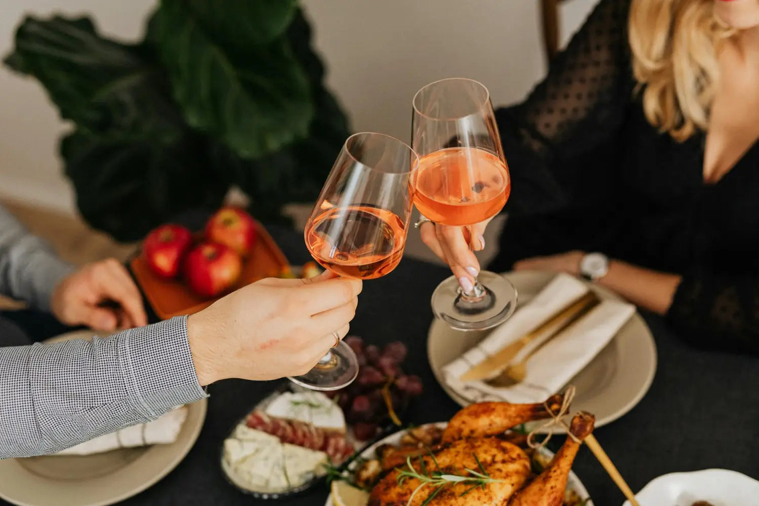Couple toasting with wine over a delicious roasted chicken dinner.